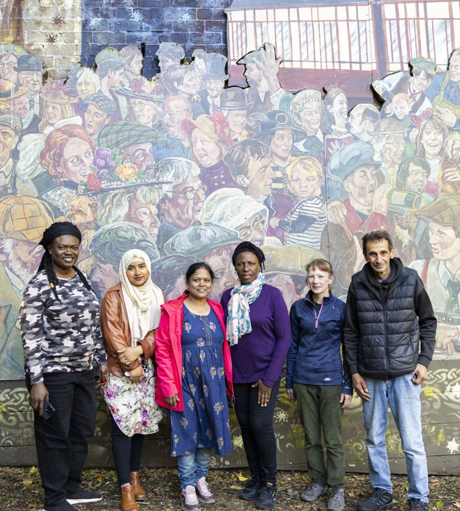 People standing in front of an art mural, smiling